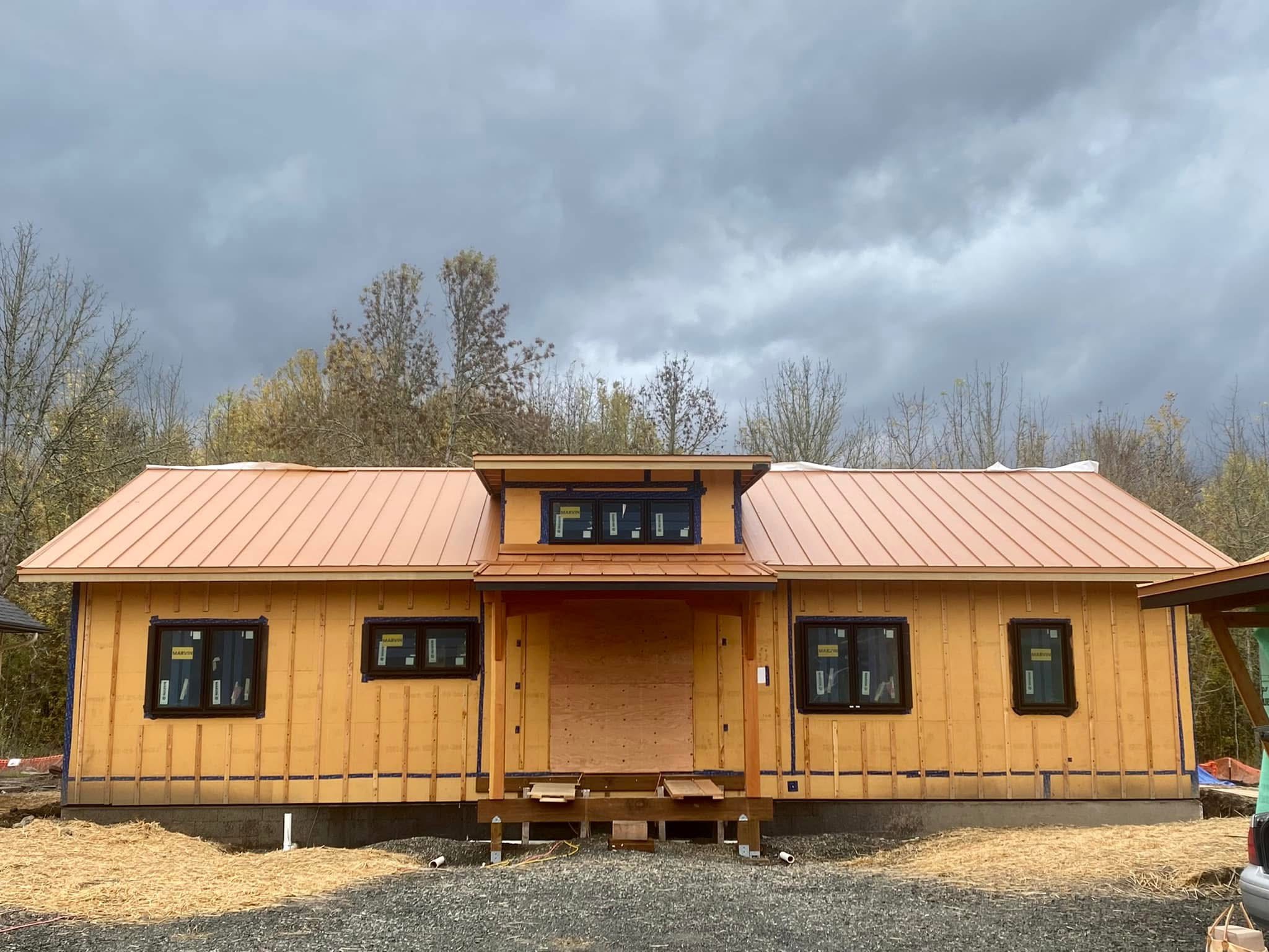 A new-build exterior with a standing seam metal roof under a dramatic storm sky