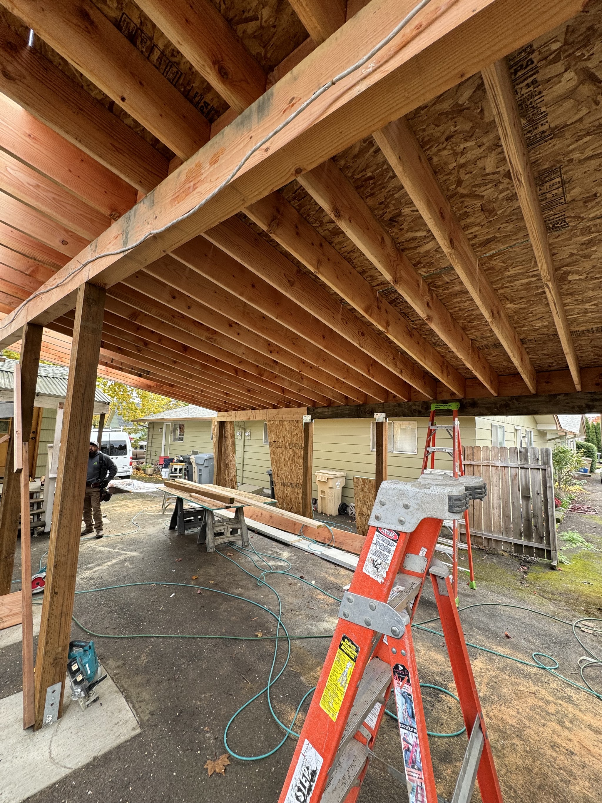 Covered patio framing under construction with a crew member on site